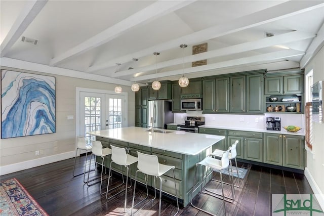 kitchen with green cabinets, a kitchen island with sink, a breakfast bar, and appliances with stainless steel finishes