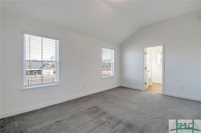 carpeted spare room with a wealth of natural light and vaulted ceiling