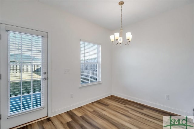 unfurnished dining area with hardwood / wood-style floors and an inviting chandelier