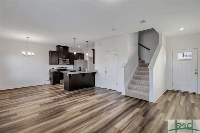 kitchen featuring dark brown cabinets, pendant lighting, a breakfast bar, and appliances with stainless steel finishes