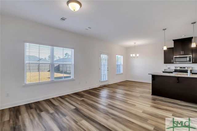 kitchen with dark brown cabinets, hardwood / wood-style flooring, a breakfast bar, a notable chandelier, and stainless steel appliances