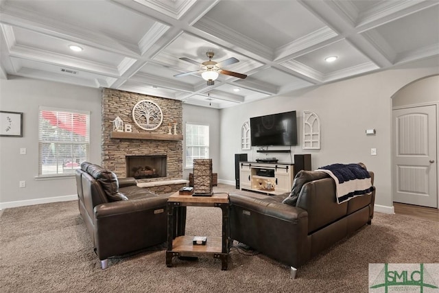 carpeted living room with coffered ceiling, beam ceiling, and a stone fireplace