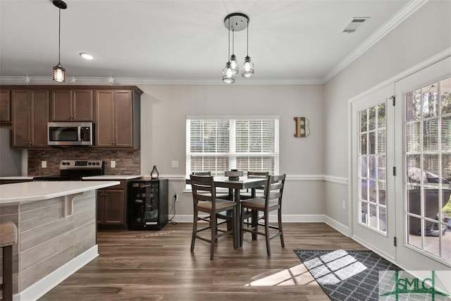 kitchen with dark brown cabinets, wine cooler, appliances with stainless steel finishes, decorative light fixtures, and ornamental molding