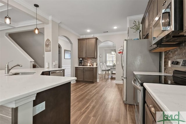 kitchen with light stone countertops, appliances with stainless steel finishes, decorative light fixtures, tasteful backsplash, and sink