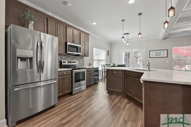 kitchen with sink, dark brown cabinets, hanging light fixtures, and appliances with stainless steel finishes