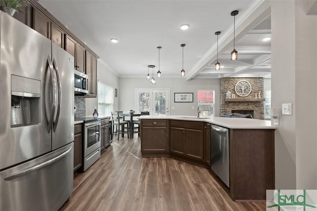 kitchen featuring stainless steel appliances, coffered ceiling, beam ceiling, and decorative light fixtures