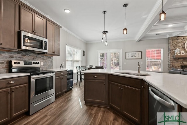 kitchen with crown molding, hanging light fixtures, appliances with stainless steel finishes, sink, and beam ceiling