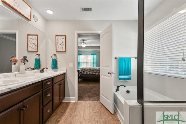 bathroom with vanity, ceiling fan, hardwood / wood-style floors, and a tub to relax in