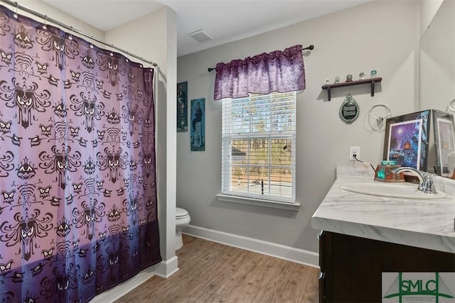 bathroom featuring hardwood / wood-style flooring, toilet, vanity, and walk in shower