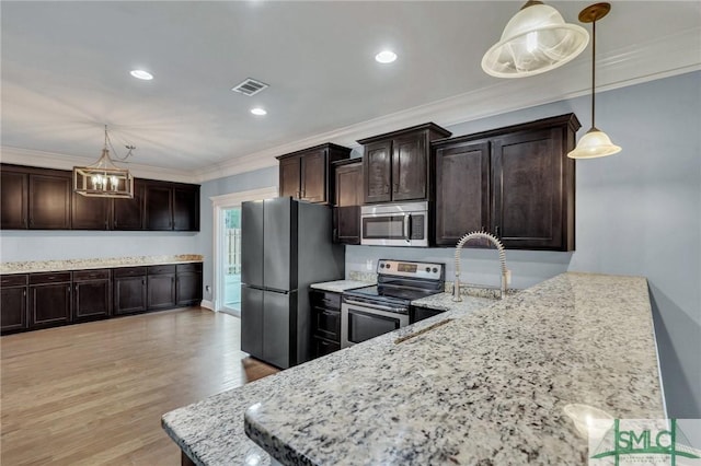 kitchen with dark brown cabinetry, stainless steel appliances, hanging light fixtures, ornamental molding, and light wood-type flooring