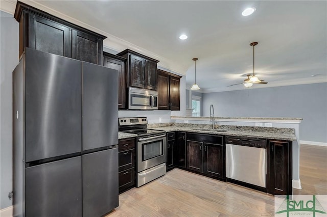 kitchen featuring pendant lighting, sink, light stone countertops, light hardwood / wood-style floors, and stainless steel appliances