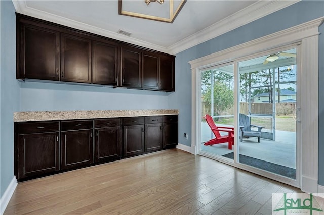 bar featuring ornamental molding, light wood-type flooring, and dark brown cabinetry