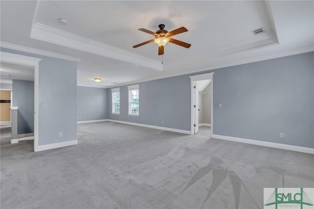 carpeted empty room with ornamental molding, ceiling fan, and a raised ceiling