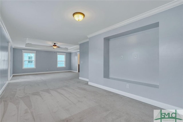 carpeted empty room with crown molding, ceiling fan, and a raised ceiling