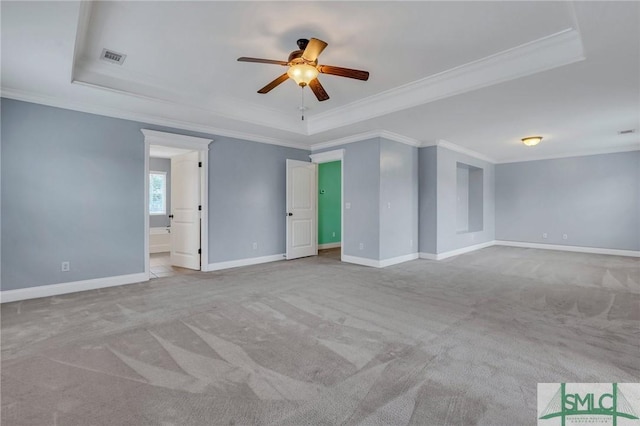 unfurnished room with ceiling fan, a raised ceiling, ornamental molding, and light carpet