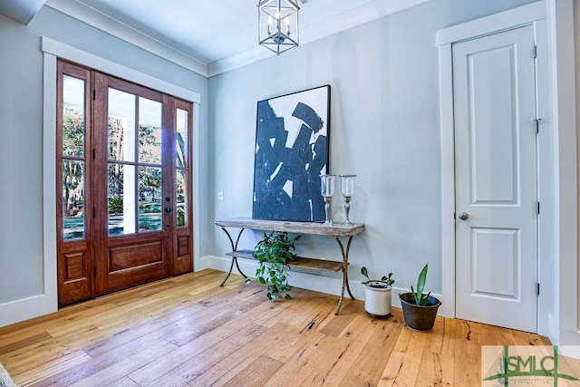 entryway featuring an inviting chandelier, crown molding, and light hardwood / wood-style flooring