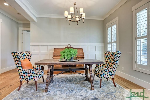 dining area with ornamental molding, a chandelier, and light wood-type flooring