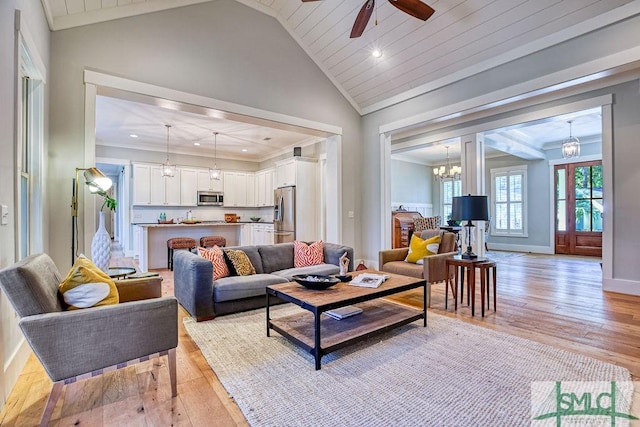 living room with lofted ceiling, light wood-type flooring, ornamental molding, wooden ceiling, and an inviting chandelier