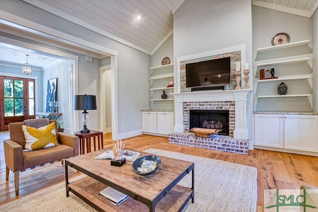 living room featuring vaulted ceiling, wooden ceiling, a fireplace, and built in shelves