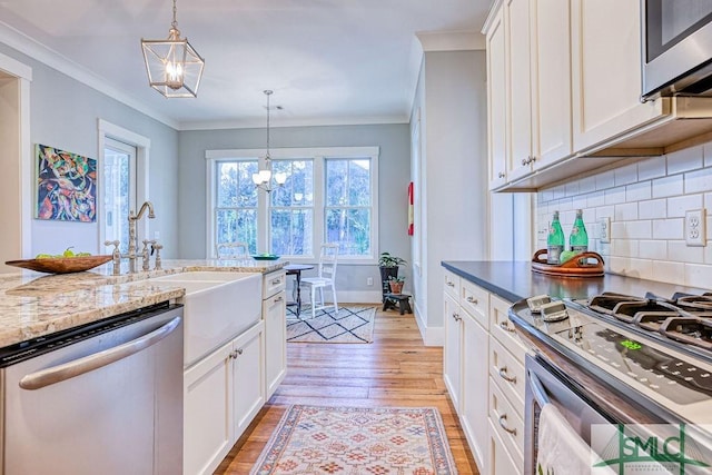 kitchen with white cabinetry, ornamental molding, appliances with stainless steel finishes, and an inviting chandelier