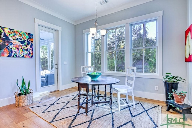 dining space featuring a notable chandelier, a wealth of natural light, wood-type flooring, and ornamental molding