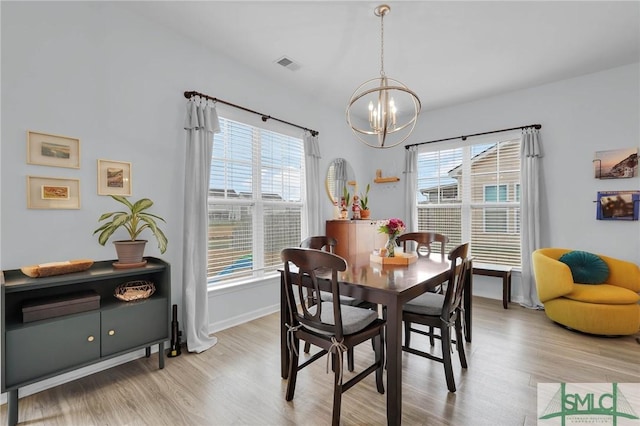 dining space featuring an inviting chandelier, a wealth of natural light, and light hardwood / wood-style floors