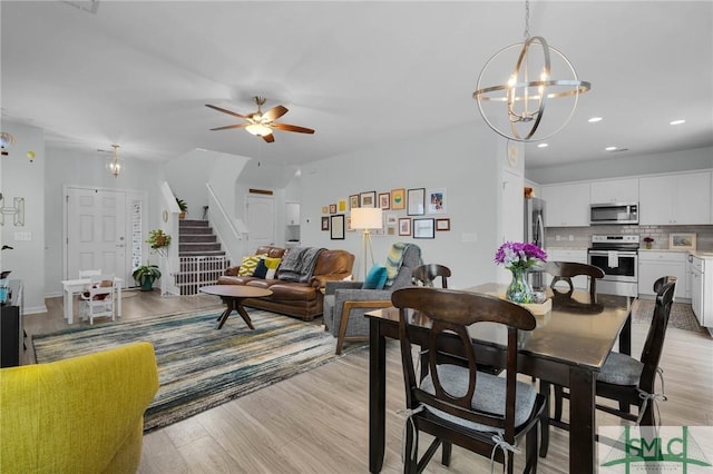 dining space with ceiling fan with notable chandelier and light wood-type flooring