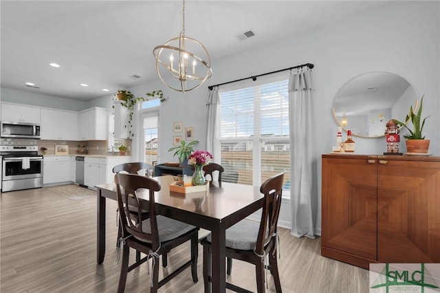 dining room featuring a notable chandelier, sink, and light wood-type flooring