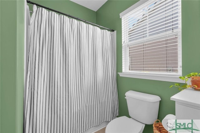 bathroom with a shower with curtain, plenty of natural light, and toilet