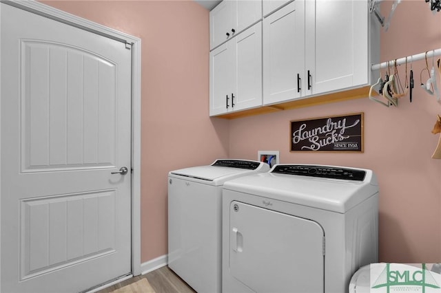 laundry area with cabinets, independent washer and dryer, and light hardwood / wood-style flooring