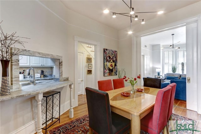 dining area with light hardwood / wood-style floors and an inviting chandelier