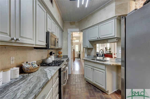 kitchen with sink, light stone countertops, and appliances with stainless steel finishes