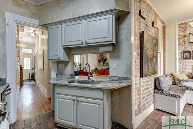 kitchen featuring sink, light stone countertops, range, ornamental molding, and a chandelier