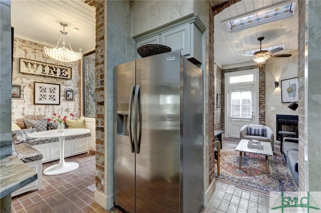 kitchen featuring decorative light fixtures, ceiling fan with notable chandelier, stainless steel fridge with ice dispenser, and a fireplace