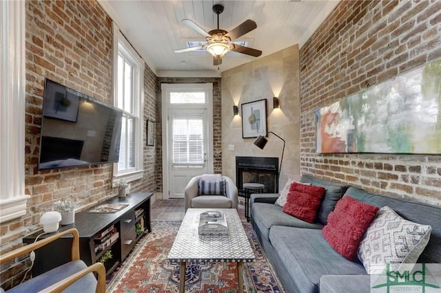 living room with a fireplace, brick wall, ceiling fan, and wood ceiling