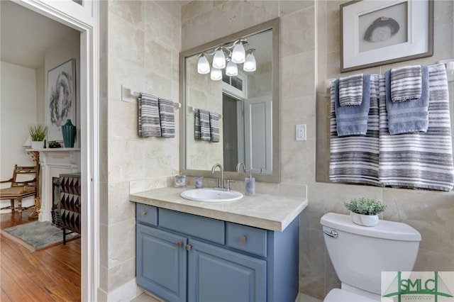 bathroom with tile walls, toilet, and vanity