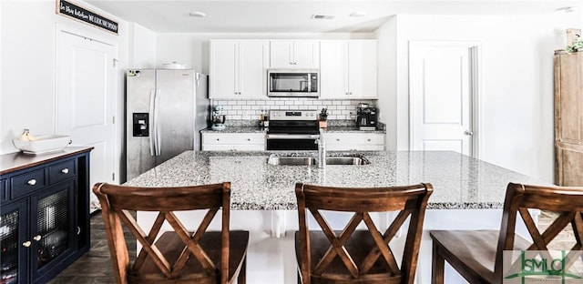 kitchen featuring light stone counters, a kitchen breakfast bar, white cabinets, and stainless steel appliances