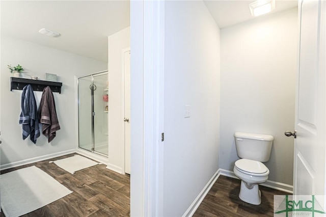 bathroom featuring hardwood / wood-style floors, toilet, and a shower with shower door