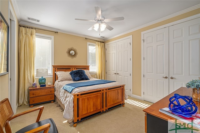 carpeted bedroom with ceiling fan, two closets, multiple windows, and crown molding