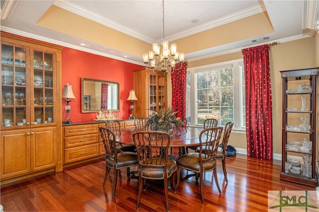 dining room featuring a notable chandelier, a raised ceiling, crown molding, and dark hardwood / wood-style flooring