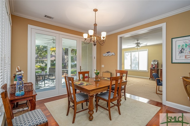 dining area with wood-type flooring, ceiling fan with notable chandelier, and ornamental molding