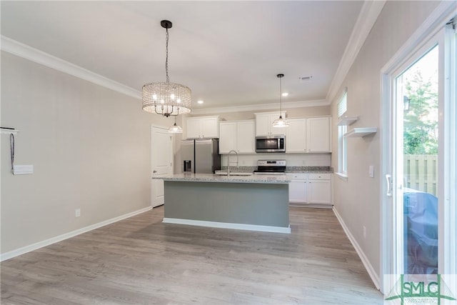 kitchen featuring appliances with stainless steel finishes, white cabinetry, hanging light fixtures, sink, and an island with sink