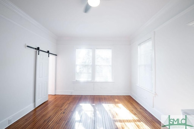 spare room with hardwood / wood-style floors, crown molding, and a barn door