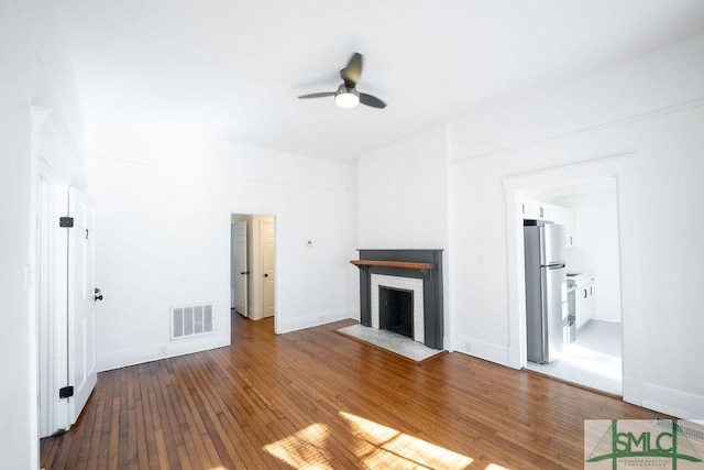 unfurnished living room featuring ceiling fan, wood-type flooring, and a fireplace