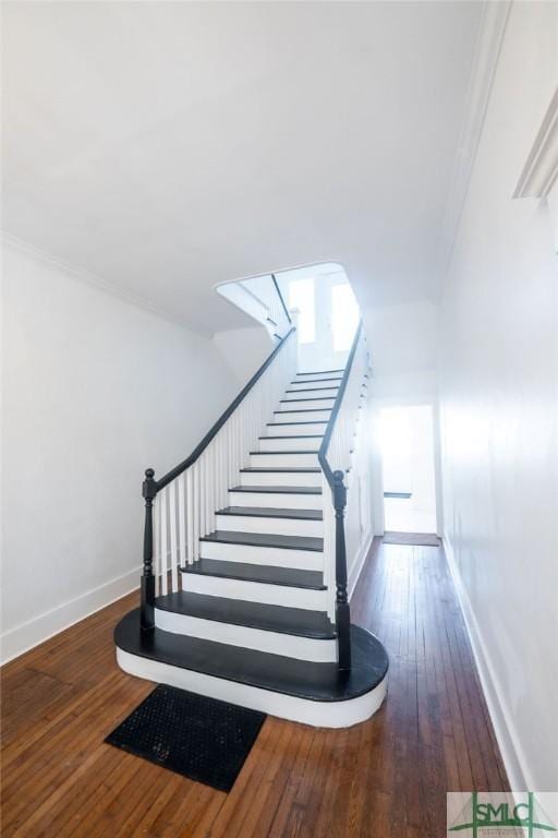 stairs with crown molding and wood-type flooring