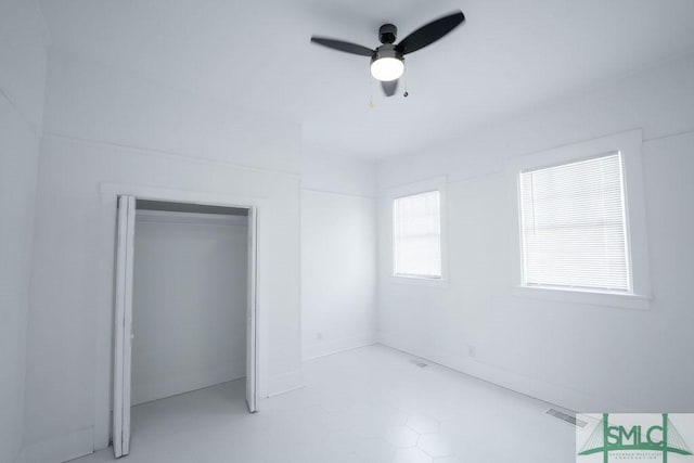 unfurnished bedroom with ceiling fan and a closet