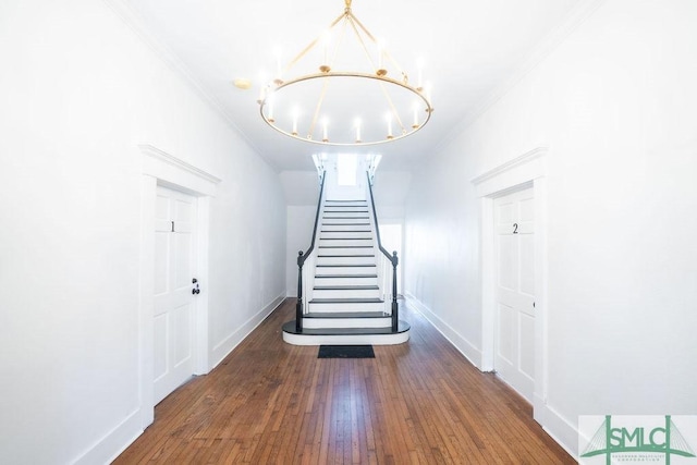 stairway featuring hardwood / wood-style flooring, ornamental molding, and an inviting chandelier