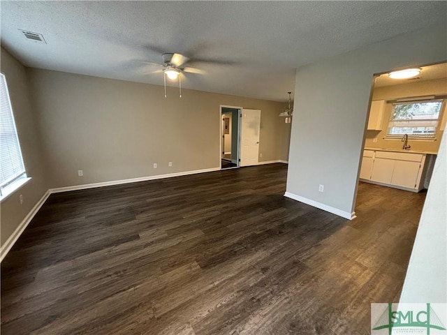 unfurnished living room with ceiling fan, dark hardwood / wood-style floors, sink, and a textured ceiling