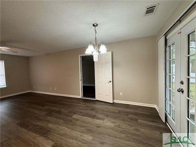 spare room featuring dark hardwood / wood-style floors, a textured ceiling, a chandelier, and french doors