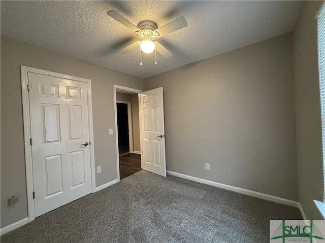 unfurnished bedroom featuring dark carpet, a textured ceiling, and ceiling fan